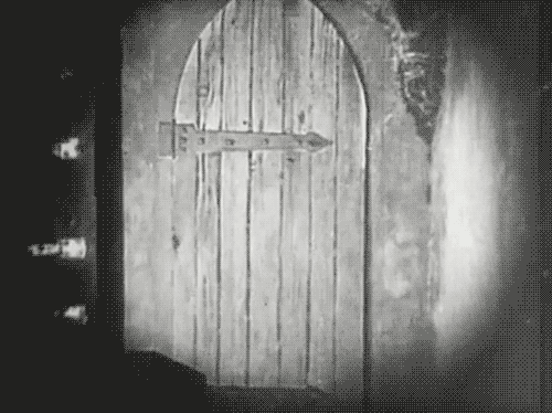 A black and white film shot of a door opening